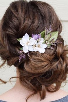 a woman with brown hair and flowers in her hair is wearing a flowered updo