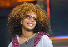 a close up of a person wearing sunglasses and a sweater with an afro hairstyle