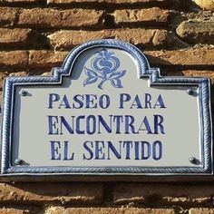 a sign that is on the side of a brick wall with writing in spanish and english