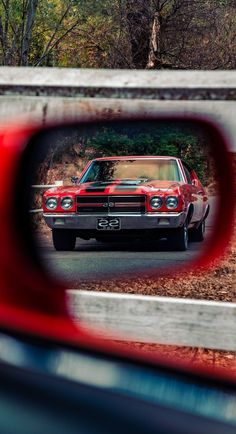 a red car is seen through a rear view mirror