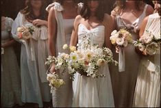 a group of bridesmaids in white dresses holding bouquets