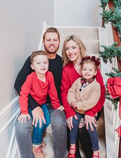 a family sitting on the stairs in front of a christmas tree