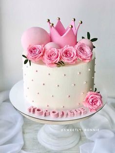 a white cake with pink flowers and a crown on top