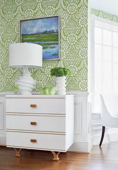 a white dresser sitting in front of a window next to a painting on the wall