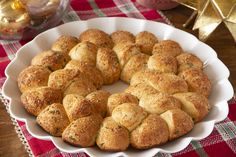 a white platter filled with rolls on top of a red and green table cloth