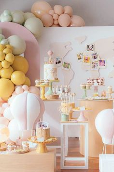 a room filled with lots of balloons and desserts on top of wooden table next to wall