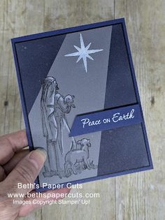 a hand holding up a card with a nativity scene on it and the words peace on earth