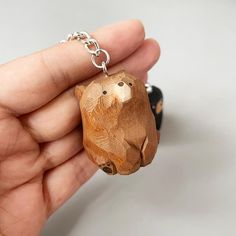 a small wooden bear keychain is held in someone's hand with a chain