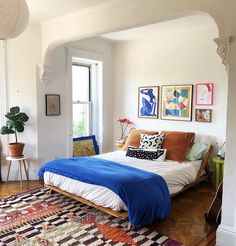 a bed sitting in the middle of a living room next to a large rug on top of a hard wood floor