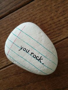 a rock with the words you rock written on it sitting on top of a wooden table