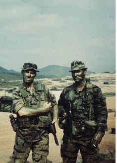 two men in camouflage standing next to each other