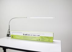 a desk lamp sitting on top of a white table next to a green box with the label slimflex led bulb lamp