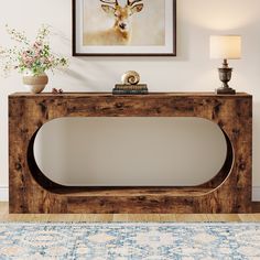 a wooden console table with a deer head on the wall above it and a lamp next to it