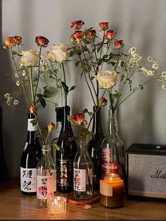 several bottles with flowers in them sitting on a table next to candles and a radio