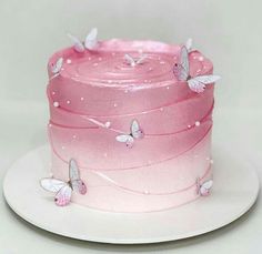 a pink and white cake with butterflies on the icing, sitting on a plate