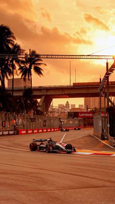 two racing cars driving down the track at sunset