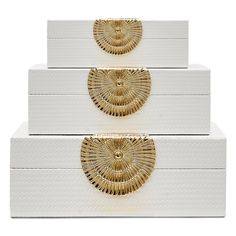 three white boxes with gold designs on the top and bottom, stacked up against each other