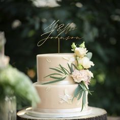 a wedding cake with white flowers and greenery sits on top of a tree stump