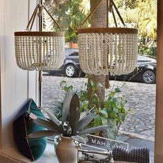 two chandeliers hanging from the ceiling in front of a window with cars parked outside