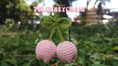 two pink crocheted cherries hanging from a branch in the grass with words tulip keychain