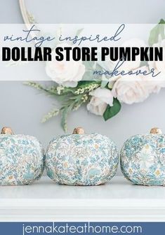 three blue and white pumpkins sitting on top of a table with flowers in the background