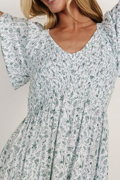 Get ready to turn heads in The Joanie Smocked Maxi Dress—your new go-to for easy, feminine style. In beautiful off-white with delicate sage floral and flutter sleeves, this dress is all about charm. And the hidden pockets keep your essentials close while you steal the show. Flowy V-neck Smocked Dress For Brunch, Summer V-neck Ruched Smocked Dress, White V-neck Smocked Dress With Smocked Back, Spring V-neck Dress With Smocked Cuffs, Bohemian Smocked V-neck Dress For Brunch, Casual Smocked Flutter Sleeve Dress For Garden Party, Spring V-neck Smocked Dress, Casual Smocked Dress With Flutter Sleeves For Garden Party, V-neck Smocked Dress With Ruffle Hem For Brunch