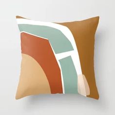 a brown and green pillow with an abstract design on the front, sitting against a white wall