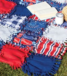 an open book on top of a red, white and blue blanket next to a basket