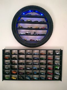 a wall mounted display case with toy cars on it and a round mirror above it