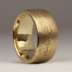 a gold wedding ring on a plain surface with some dirt all over it and the edges are slightly textured