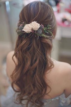 a woman with long brown hair and flowers in her hair is looking at the mirror