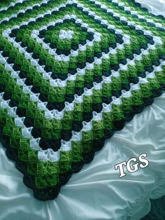 a green and white afghan on a bed with the words iggs written below it