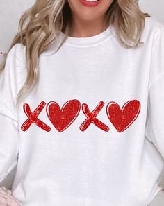 a woman wearing a white sweatshirt with red xoxo hearts on it