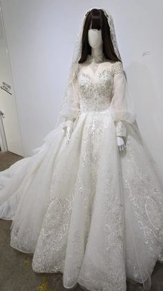 a mannequin dressed in a wedding dress with long sleeves and a veil on display