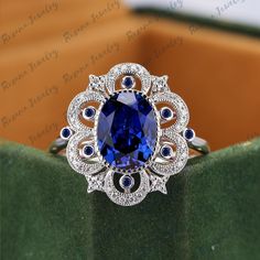 a ring with a blue stone surrounded by white sapphires and diamonds on a green surface