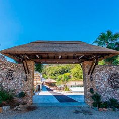 the entrance to a resort with stone walls and a thatched roof over an entry way