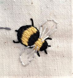 a black and yellow bee sitting on top of a white cloth