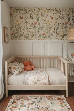 a small white bed sitting next to a window in a room with floral wallpaper