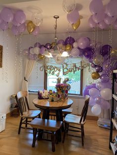 a birthday party with purple and gold balloons hanging from the ceiling, along with decorations