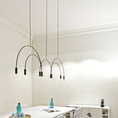 an empty kitchen with white counters and black lights hanging from the ceiling over the stove