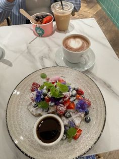 a person sitting at a table with two cups of coffee and desserts on it