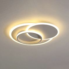 two circular lights on the ceiling in a white room with light coming from one end