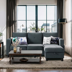 a living room with a gray couch and coffee table in front of two large windows