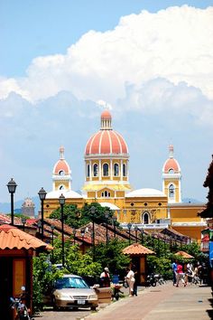 people are walking down the street in front of buildings with orange domes on top and blue sky above