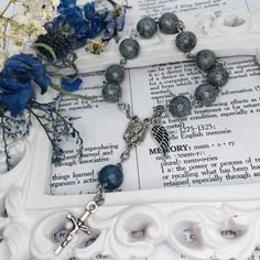 the rosary is laying on top of an open book with blue flowers in front of it