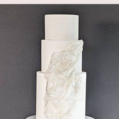 a three tiered cake with white frosting and a large piece of animal on top