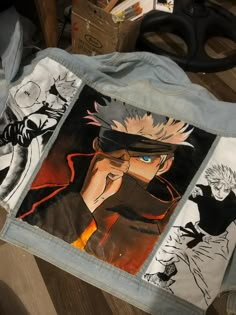 the back of a jacket with pictures of anime characters painted on it, sitting on top of a wooden table