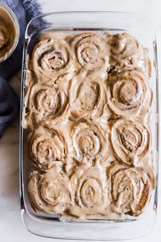 a pan filled with cinnamon rolls covered in icing