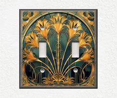 an art deco light switch plate cover in gold and green with two lights on each side