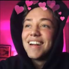 a man wearing a hoodie with hearts on it's head and smiling at the camera